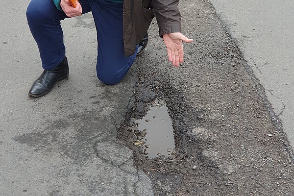 John James pointing out a bad pothole in Castle Square in Melbourne