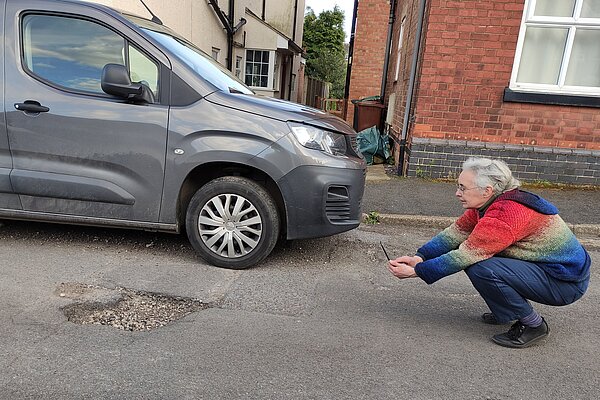 Lucy Care photographing and reporting potholes